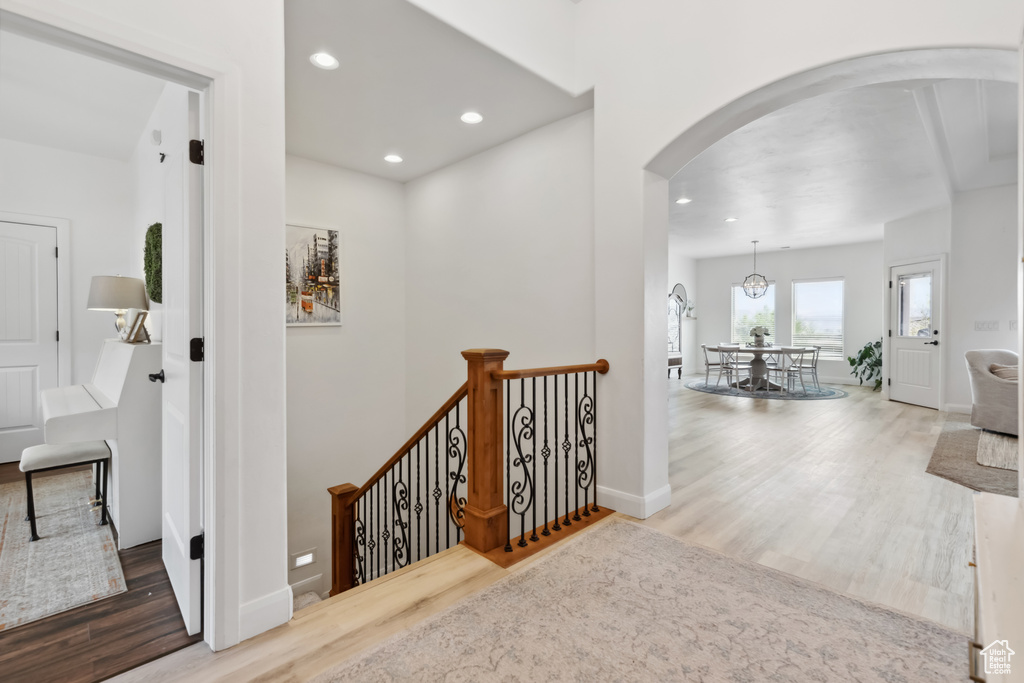 Hall with recessed lighting, arched walkways, an upstairs landing, and wood finished floors