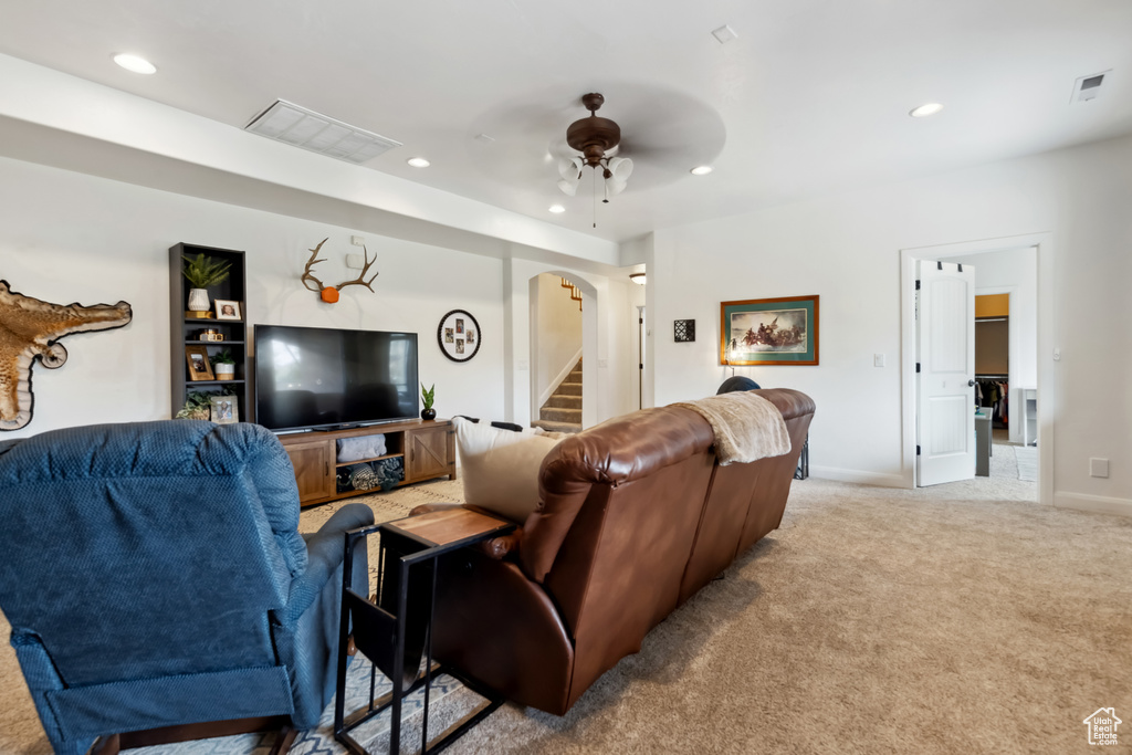 Carpeted living room with arched walkways, a ceiling fan, visible vents, and recessed lighting