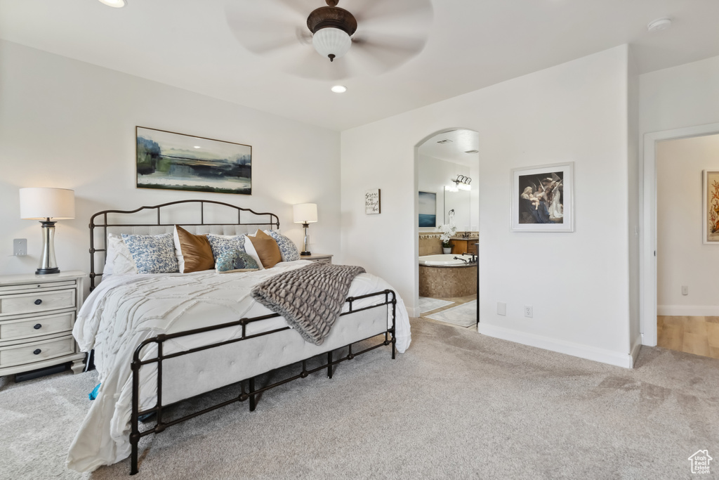 Bedroom featuring arched walkways, carpet flooring, baseboards, and ensuite bath