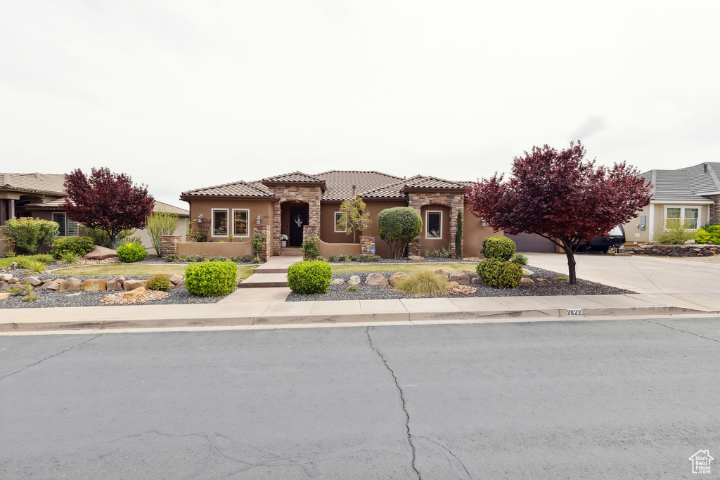 Mediterranean / spanish house featuring concrete driveway, a tile roof, a garage, and stucco siding
