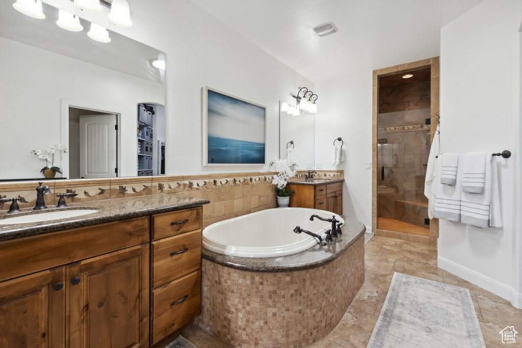 Full bathroom featuring a sink, a tile shower, two vanities, and a garden tub