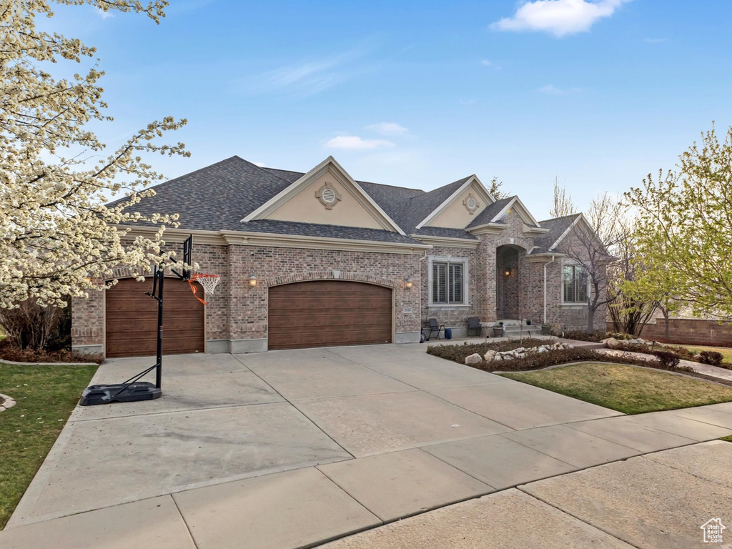 View of front of property with roof with shingles, an attached garage, a front lawn, and concrete driveway