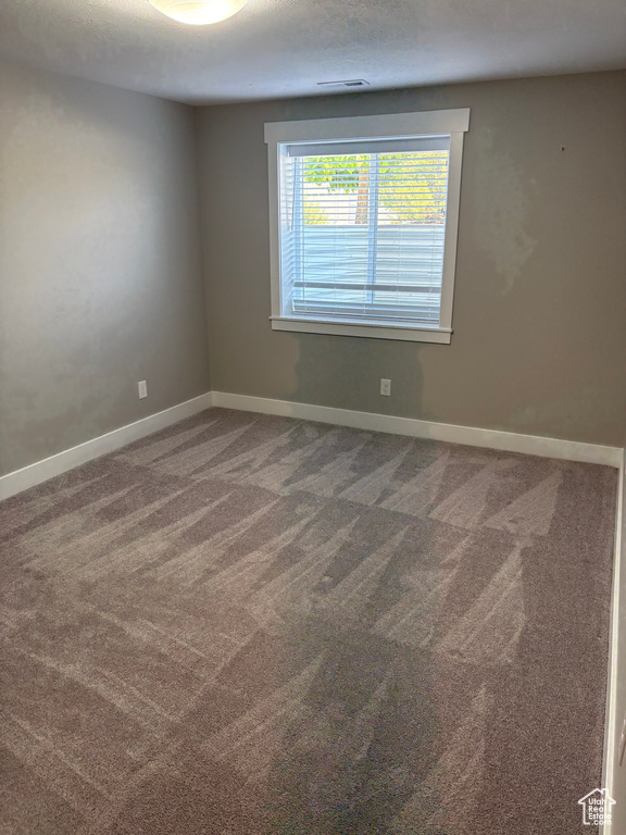 Carpeted empty room featuring baseboards