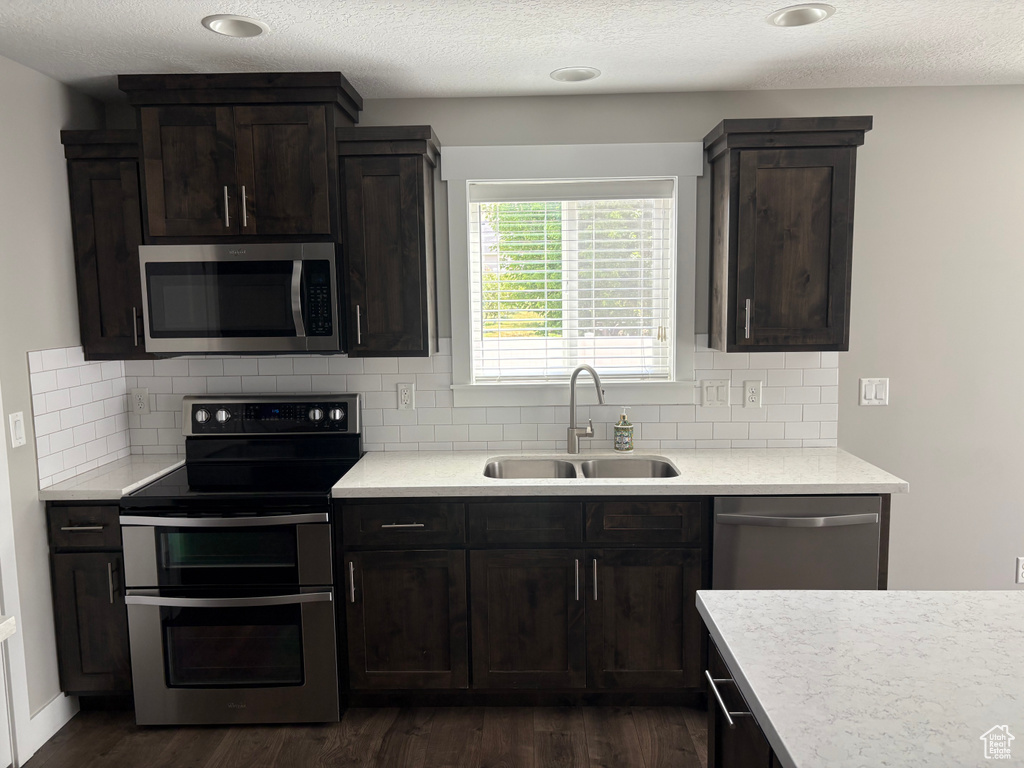 Kitchen with stainless steel appliances, dark wood-style flooring, light countertops, tasteful backsplash, and a textured ceiling