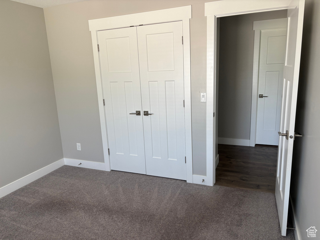 Unfurnished bedroom featuring dark colored carpet and a closet