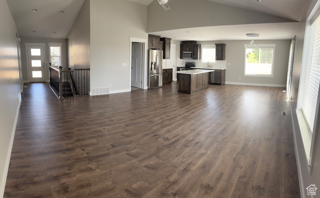 Unfurnished living room with vaulted ceiling and dark wood-style floors