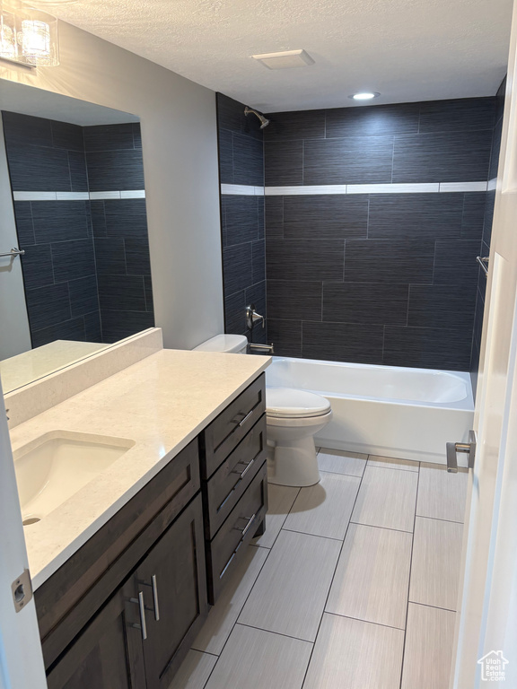 Bathroom with vanity, a textured ceiling, and tub / shower combination