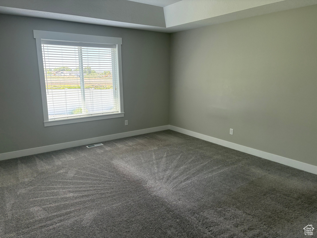 Empty room featuring dark carpet and baseboards