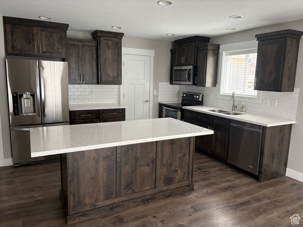 Kitchen featuring stainless steel appliances, dark brown cabinets, decorative backsplash, a center island, and recessed lighting