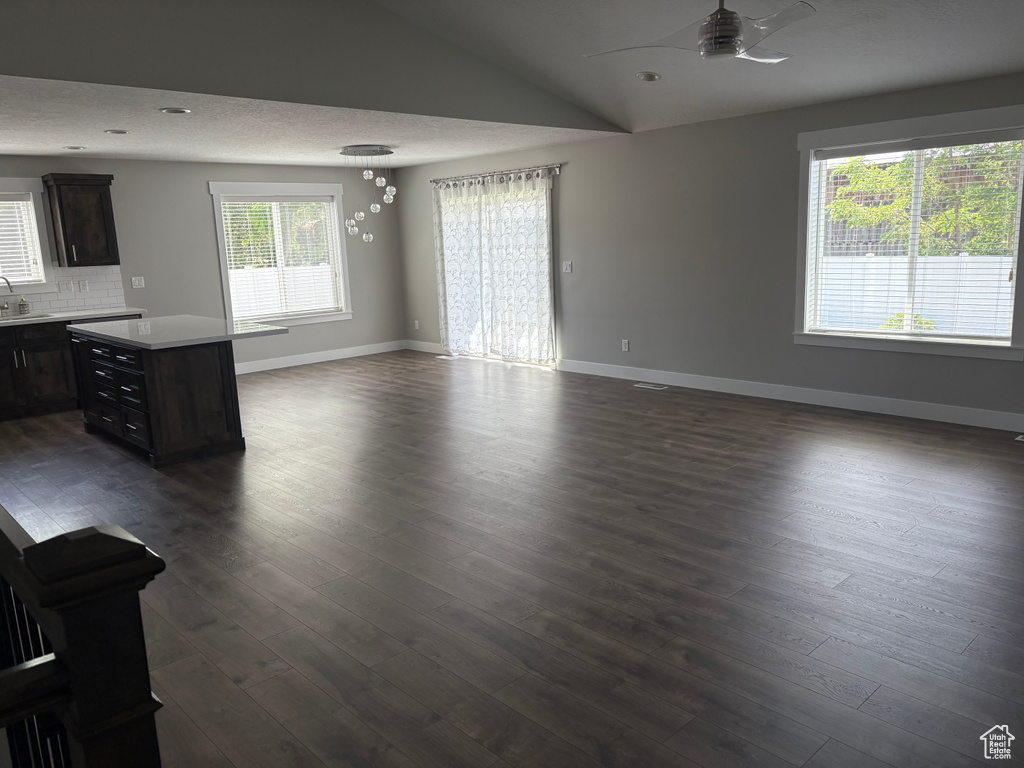 Unfurnished living room with ceiling fan, dark wood finished floors, and vaulted ceiling