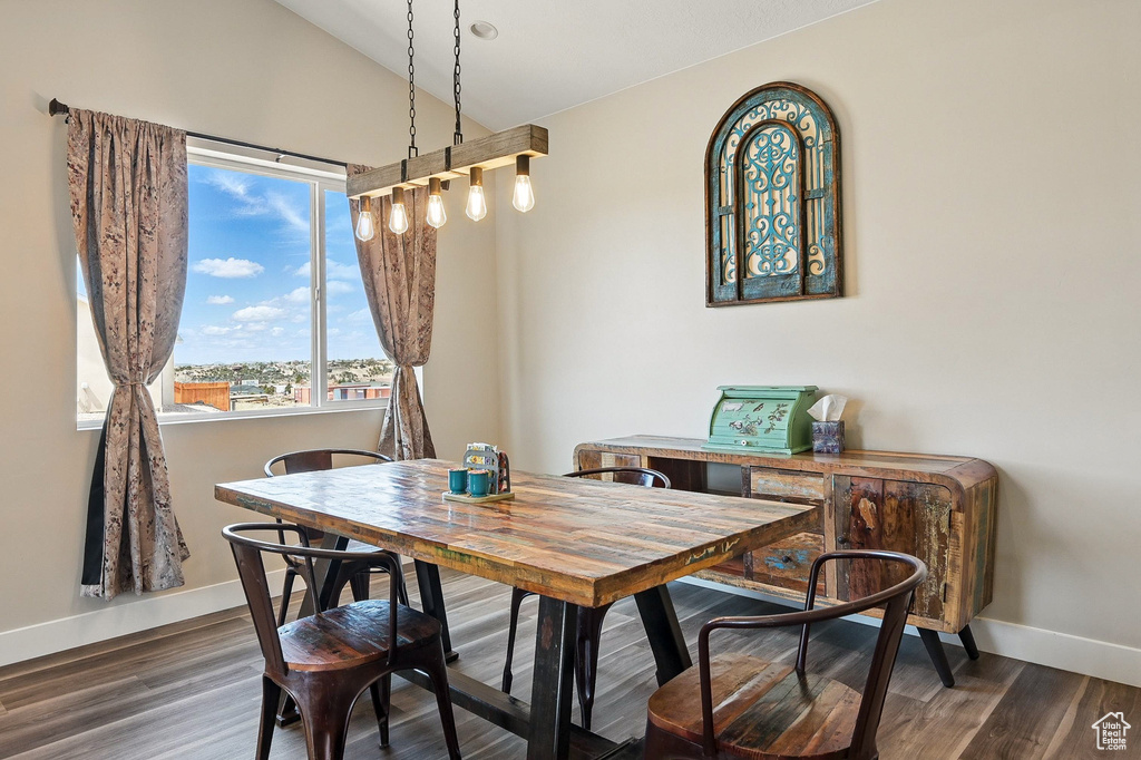 Dining space with wood finished floors, baseboards, and vaulted ceiling