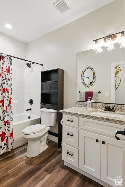 Full bath with shower / tub combo, vanity, toilet, visible vents, and wood finished floors
