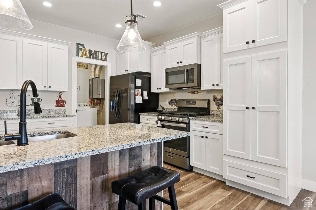 Kitchen featuring a sink, washer / clothes dryer, white cabinets, and stainless steel appliances