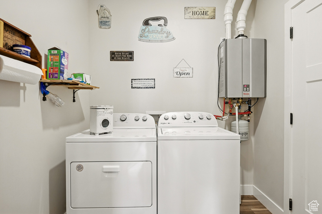 Clothes washing area with baseboards, separate washer and dryer, laundry area, wood finished floors, and water heater
