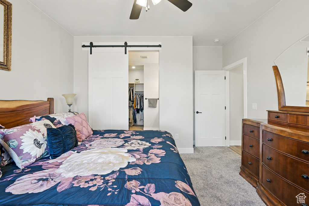 Carpeted bedroom with a barn door, baseboards, and a ceiling fan