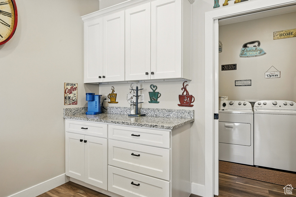 Washroom featuring laundry area, washing machine and clothes dryer, baseboards, and dark wood-style floors