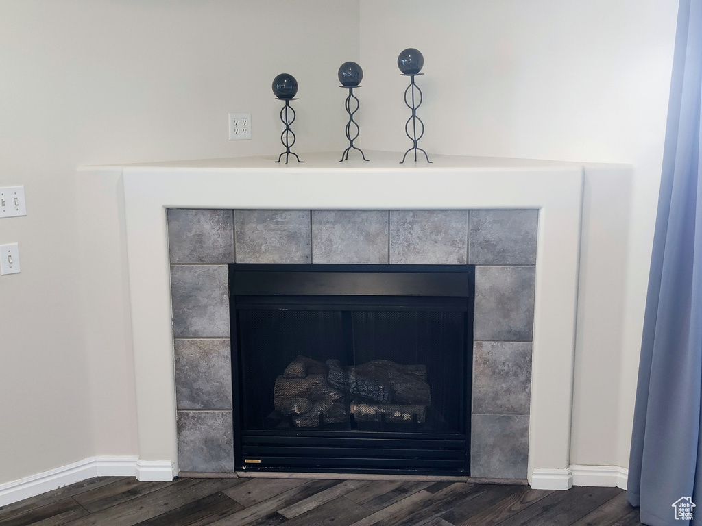 Detailed view of a tile fireplace, wood finished floors, and baseboards