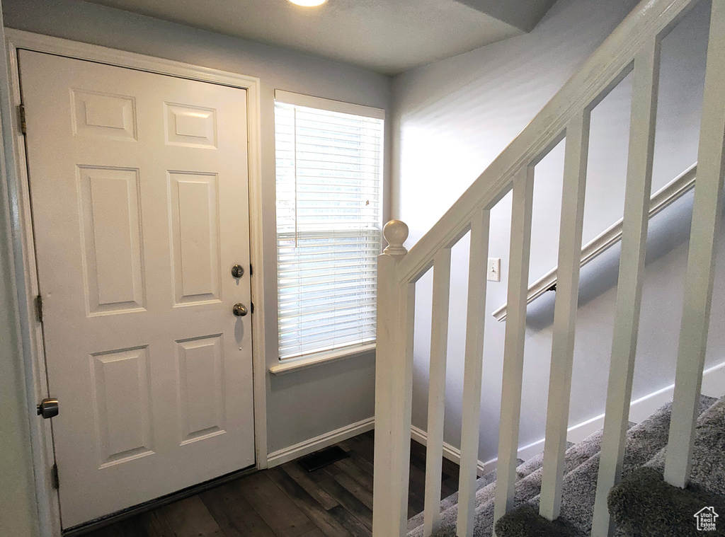 Foyer with dark wood-type flooring, stairs, and baseboards