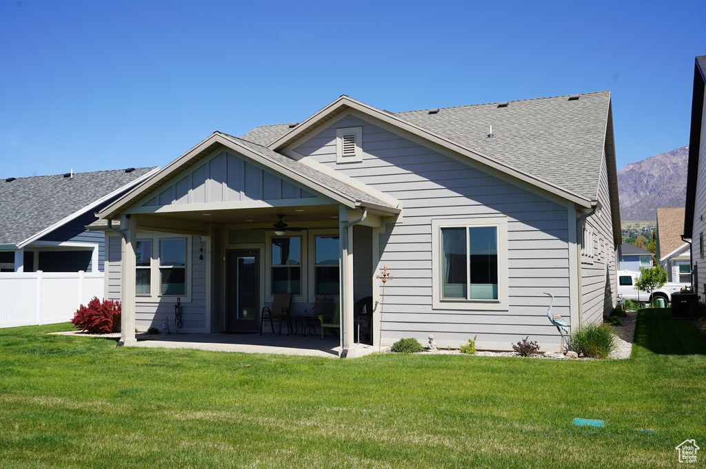 Back of house with fence, ceiling fan, a yard, and a patio area