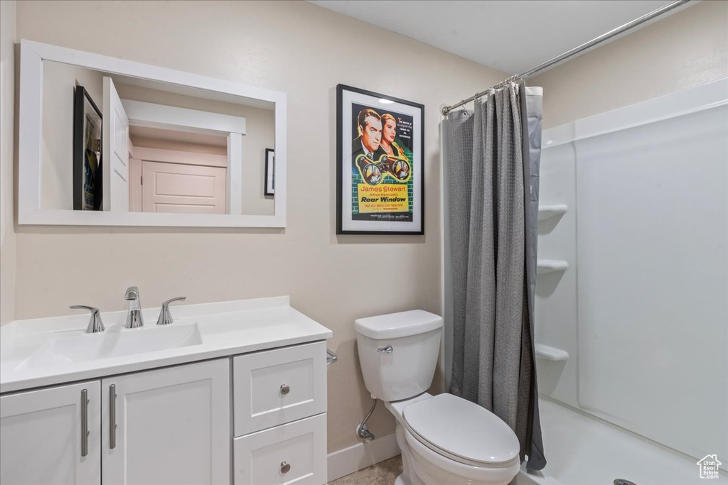 Bathroom featuring a shower stall, toilet, vanity, and baseboards