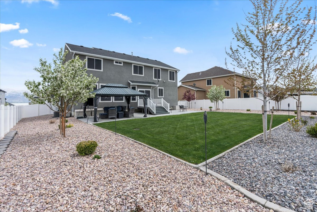 Rear view of property with a fenced backyard, a gazebo, a patio area, stucco siding, and an outdoor living space