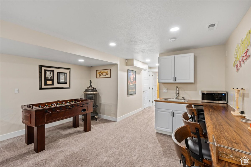 Game room featuring baseboards, a sink, recessed lighting, and light colored carpet