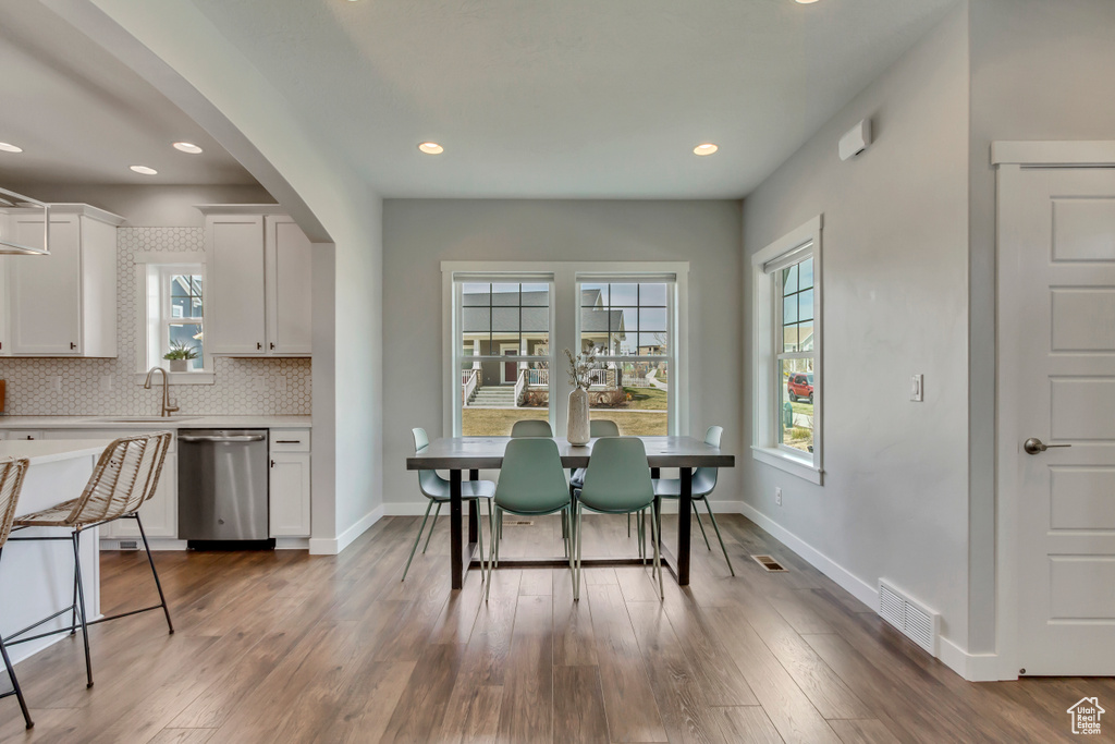 Dining space with arched walkways, wood finished floors, baseboards, and visible vents