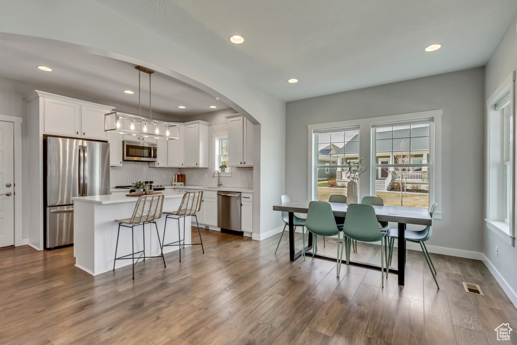 Kitchen with dark wood finished floors, tasteful backsplash, visible vents, light countertops, and stainless steel appliances