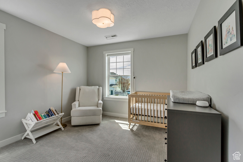 Bedroom featuring a crib, baseboards, visible vents, and carpet floors