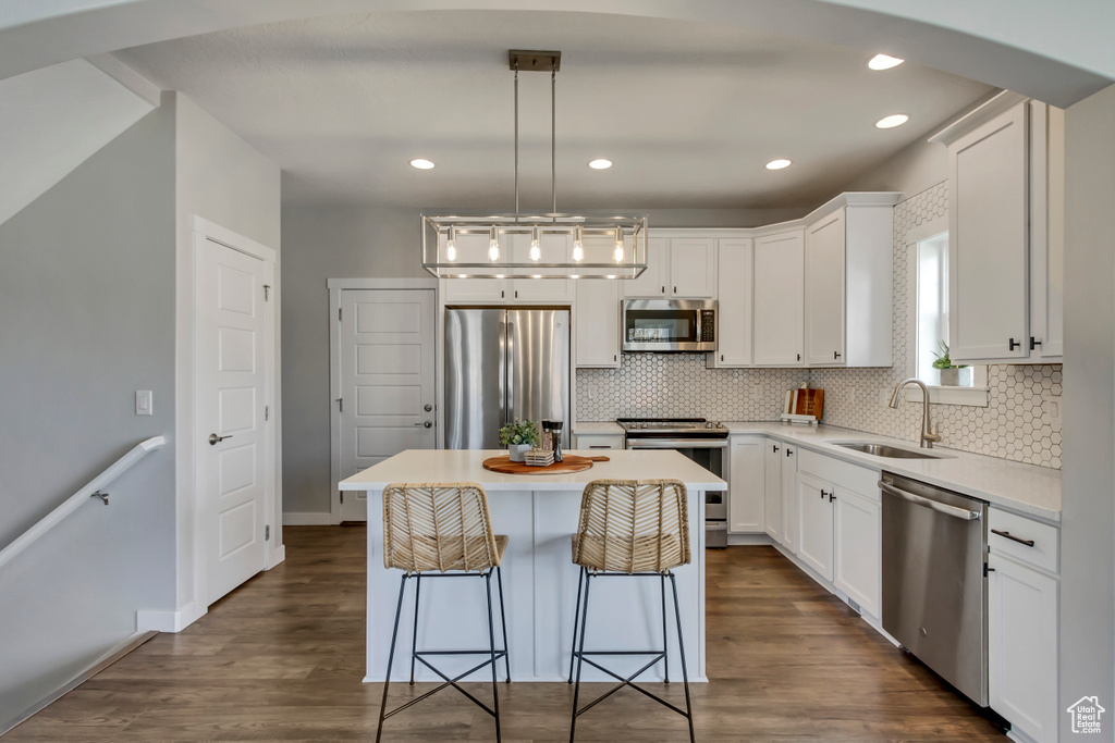 Kitchen with dark wood-type flooring, white cabinetry, a sink, and appliances with stainless steel finishes