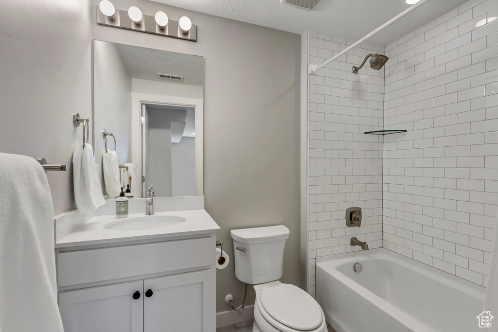 Full bathroom featuring vanity, shower / tub combination, a textured ceiling, toilet, and visible vents