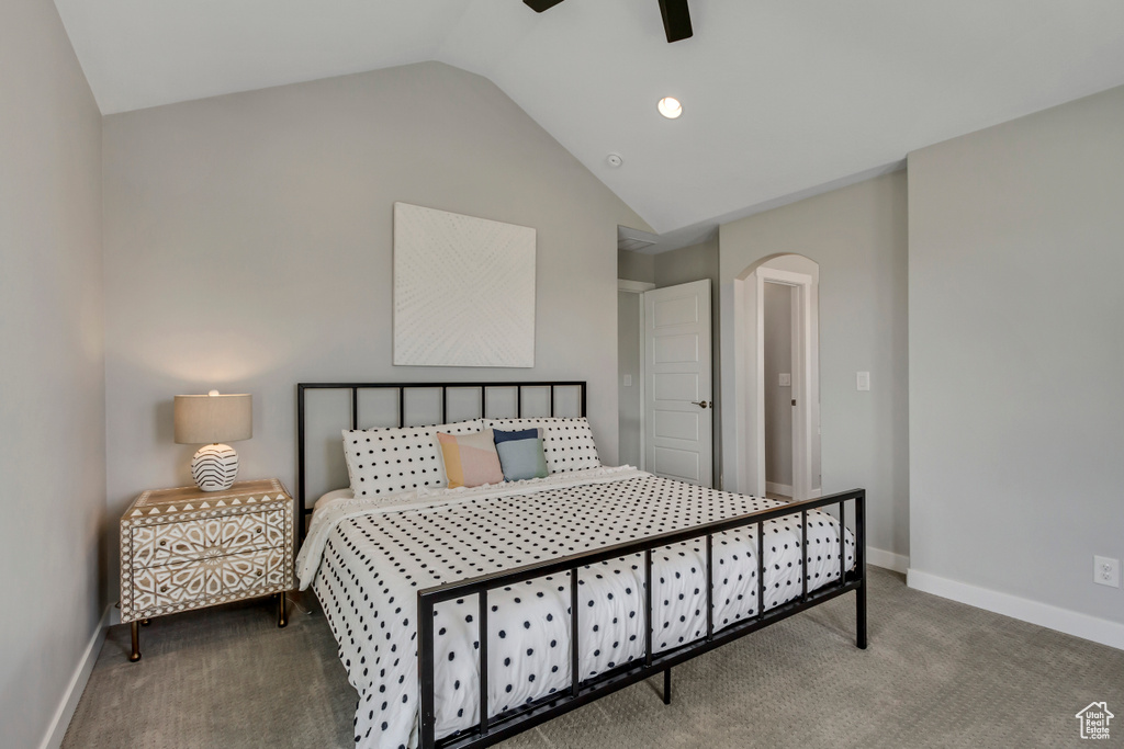 Carpeted bedroom with arched walkways, baseboards, a ceiling fan, and lofted ceiling