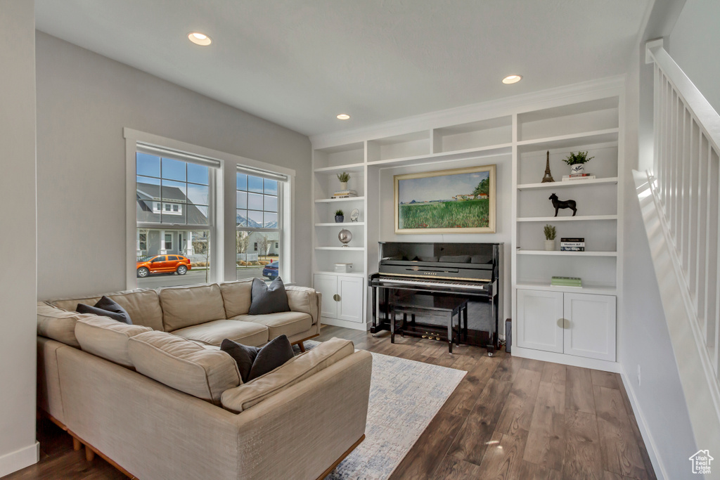 Living room featuring recessed lighting, built in shelves, dark wood-style floors, and baseboards