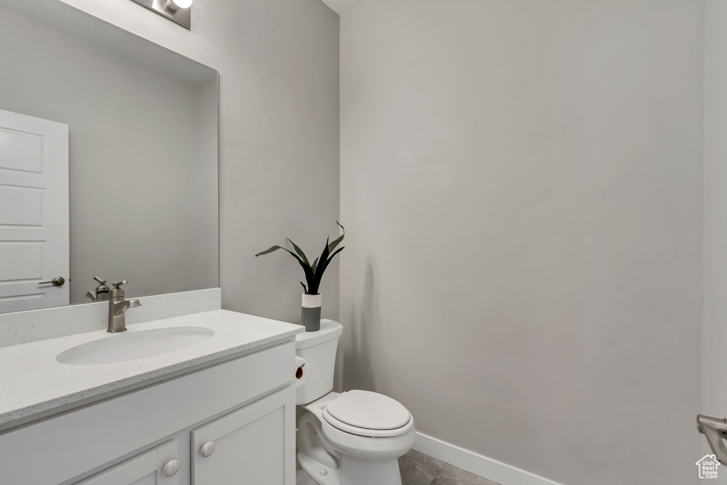 Bathroom featuring toilet, vanity, and baseboards