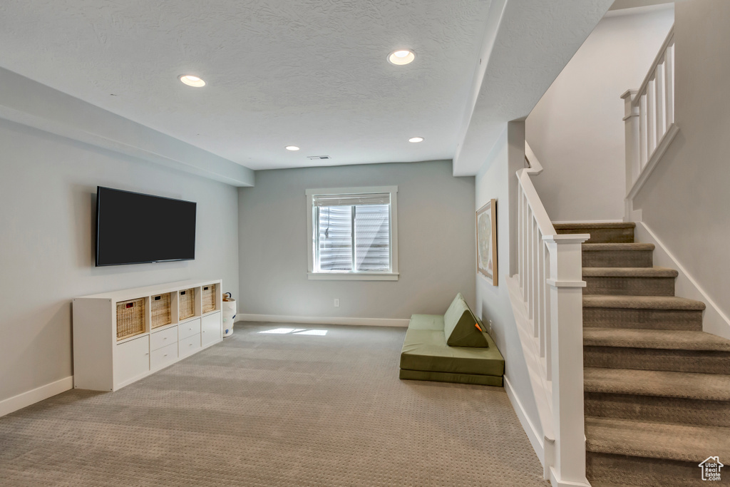 Unfurnished living room with baseboards, recessed lighting, a textured ceiling, carpet floors, and stairs