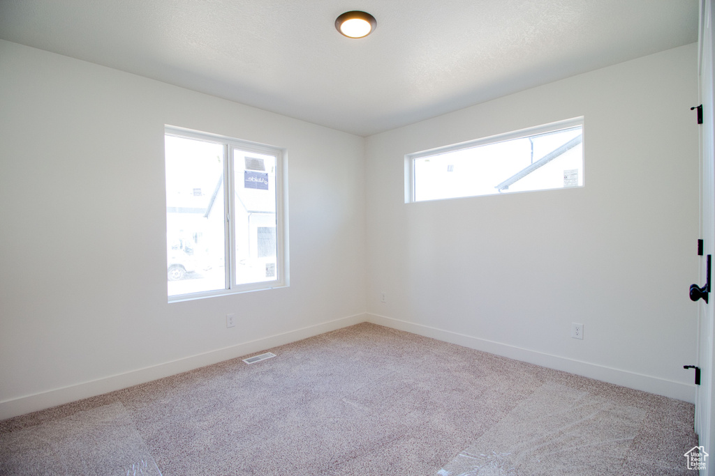 Unfurnished room featuring carpet flooring, visible vents, and baseboards