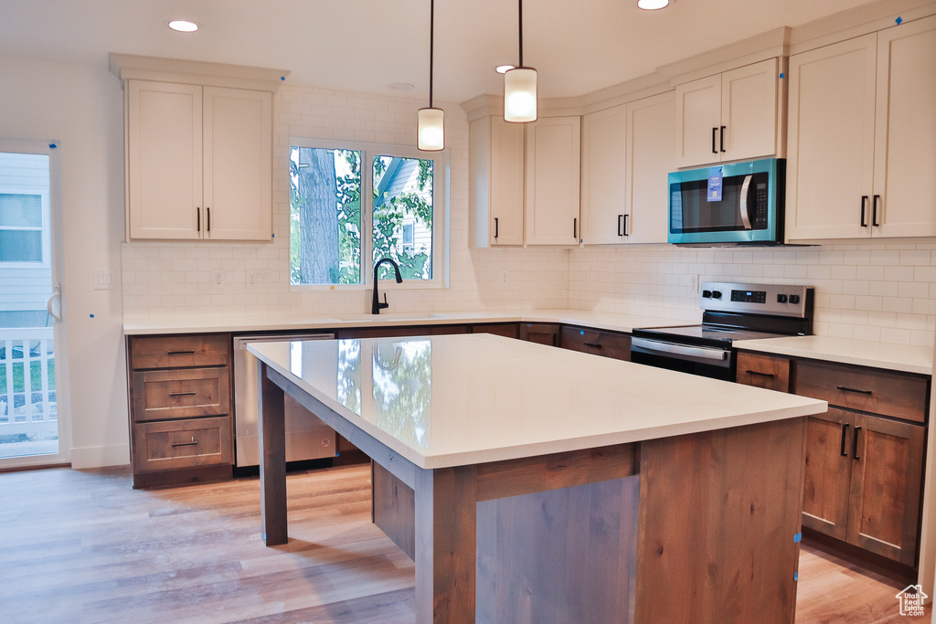 Kitchen with appliances with stainless steel finishes, recessed lighting, a sink, light countertops, and light wood-style floors