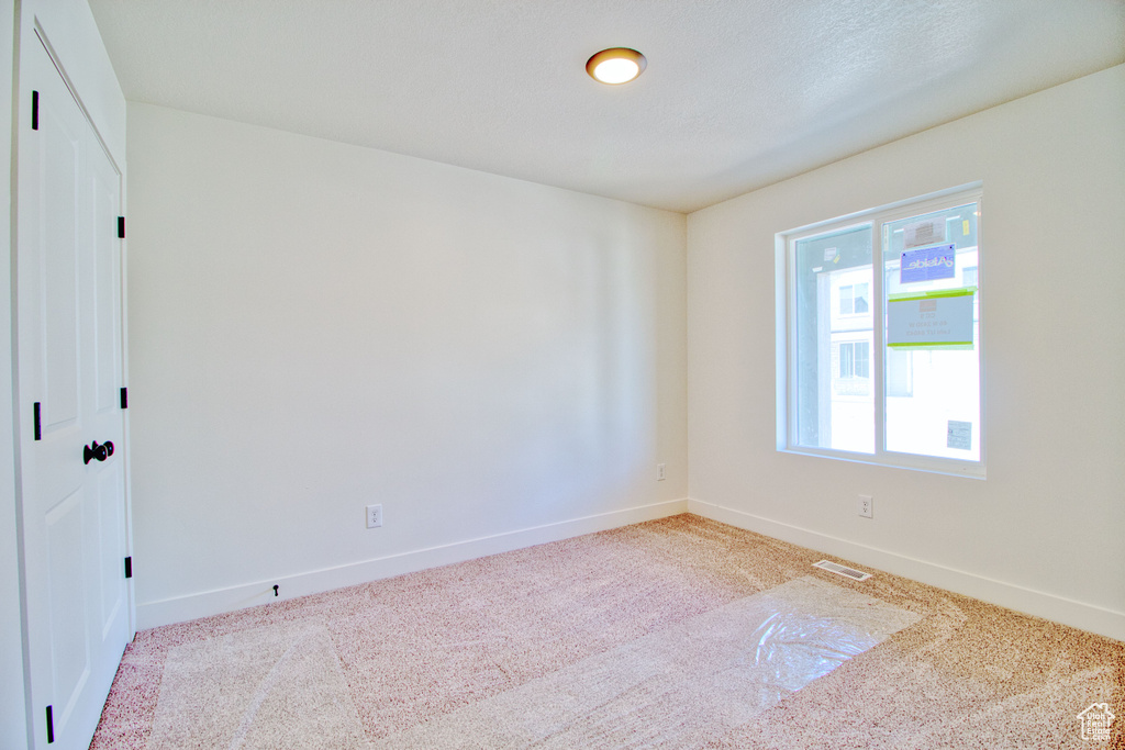 Carpeted spare room with baseboards and visible vents