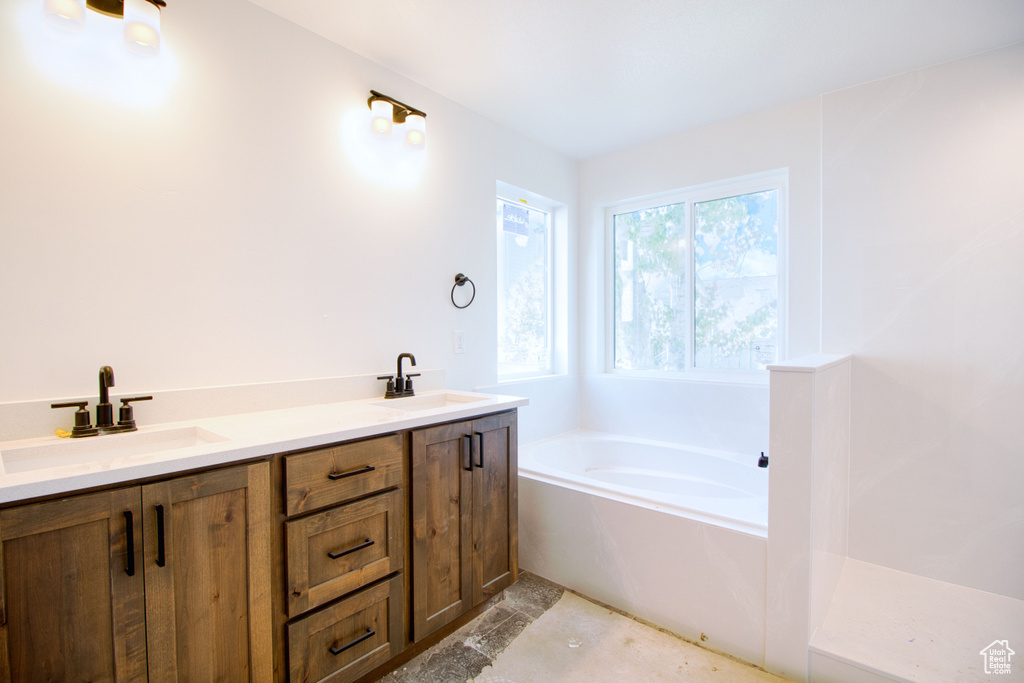 Bathroom with a sink, double vanity, and a garden tub
