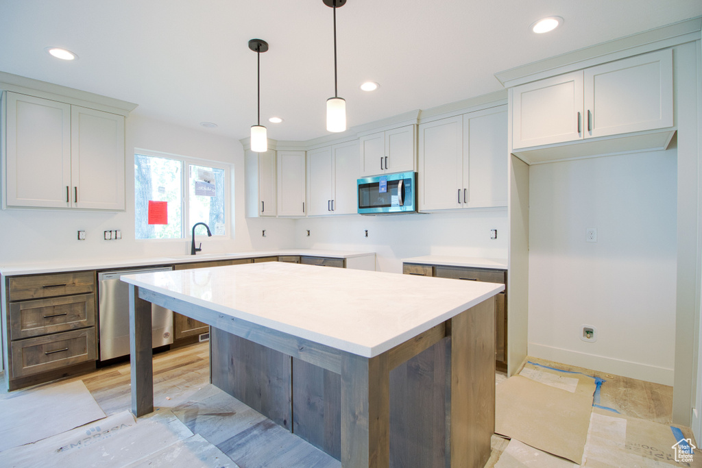 Kitchen with decorative light fixtures, stainless steel appliances, a kitchen island, and recessed lighting