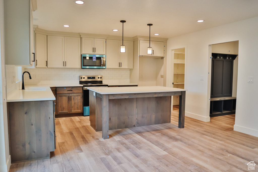 Kitchen featuring stainless steel appliances, a sink, backsplash, recessed lighting, and light wood-style floors