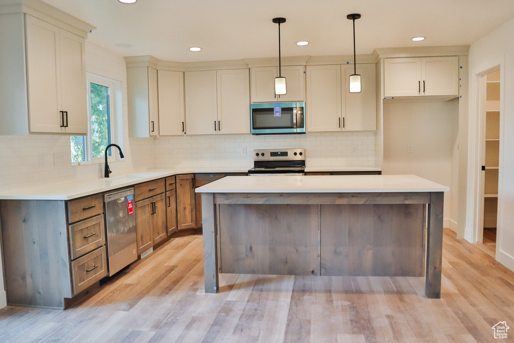 Kitchen featuring appliances with stainless steel finishes, a sink, light wood-style flooring, light countertops, and recessed lighting