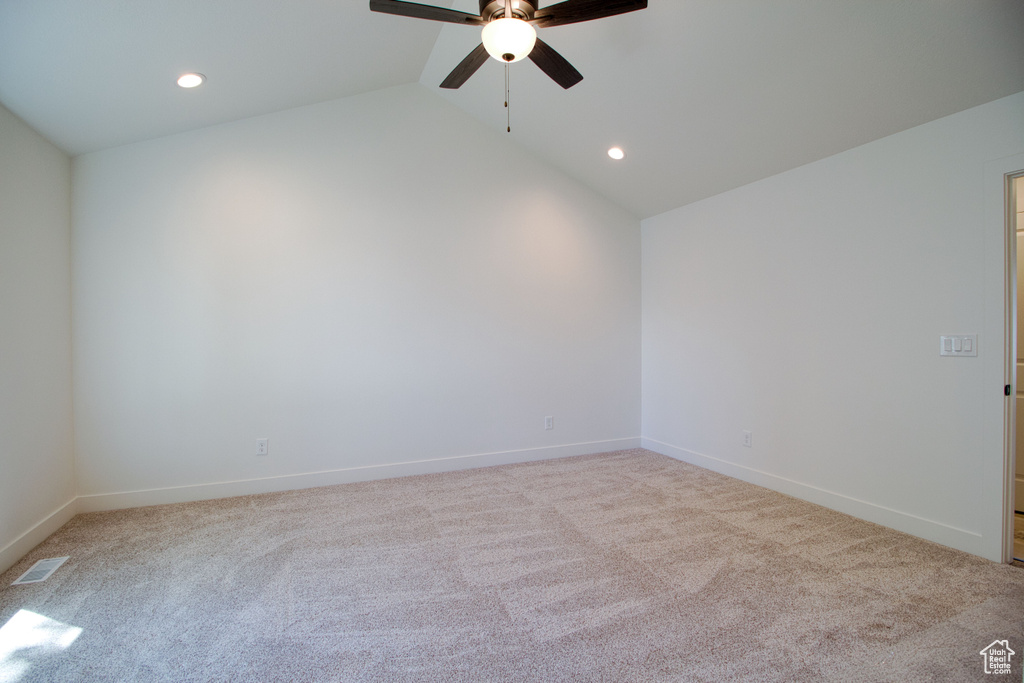 Carpeted spare room featuring visible vents, recessed lighting, vaulted ceiling, a ceiling fan, and baseboards