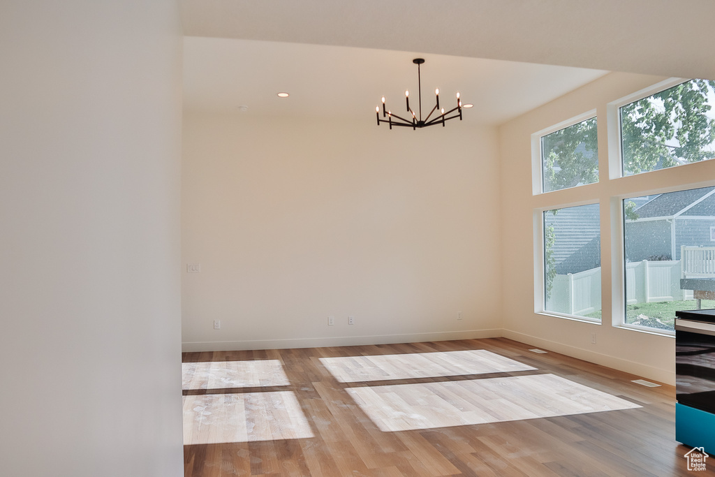 Unfurnished dining area featuring a chandelier, wood finished floors, baseboards, and recessed lighting