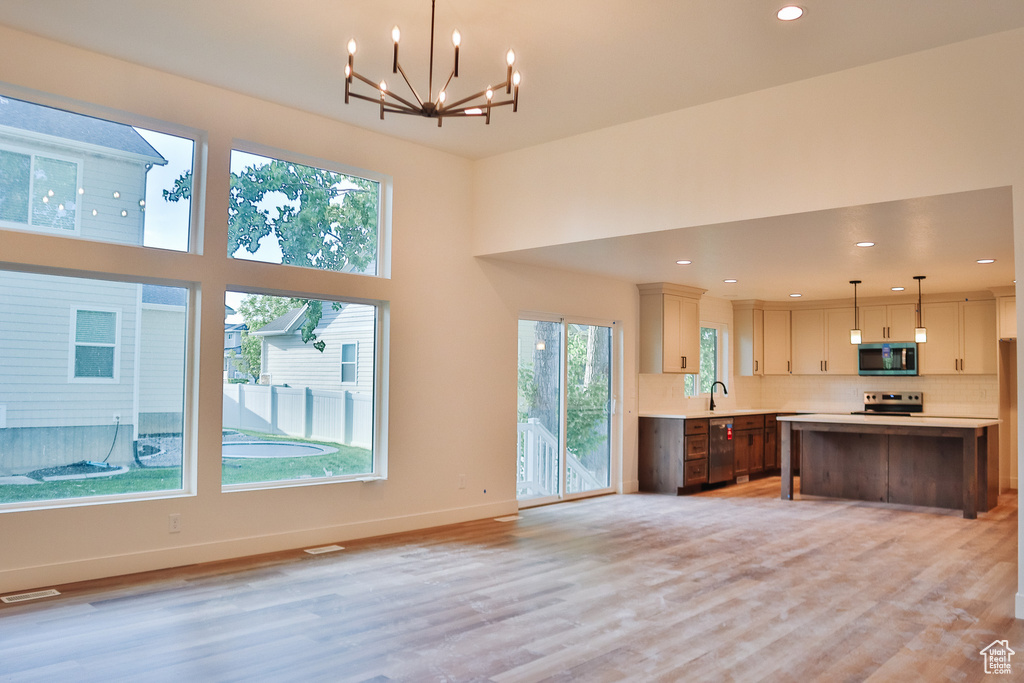 Kitchen with stainless steel appliances, light countertops, a chandelier, tasteful backsplash, and baseboards