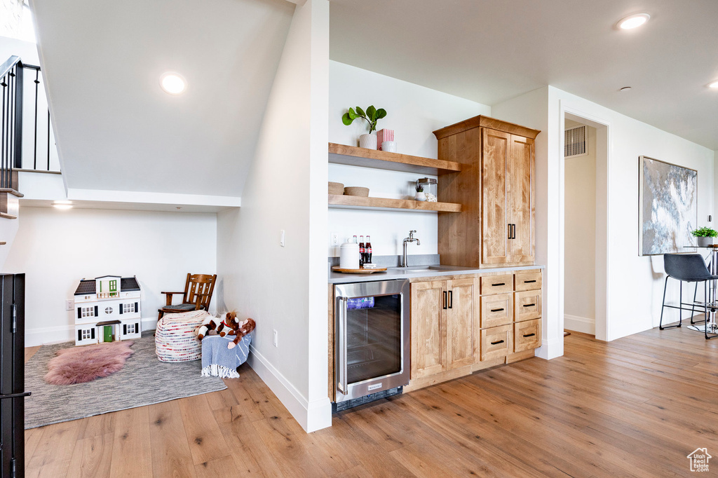 Indoor wet bar featuring beverage cooler, light wood-type flooring, baseboards, and recessed lighting