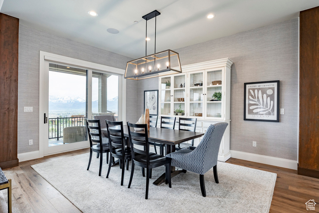 Dining area with wallpapered walls, baseboards, a chandelier, and wood finished floors