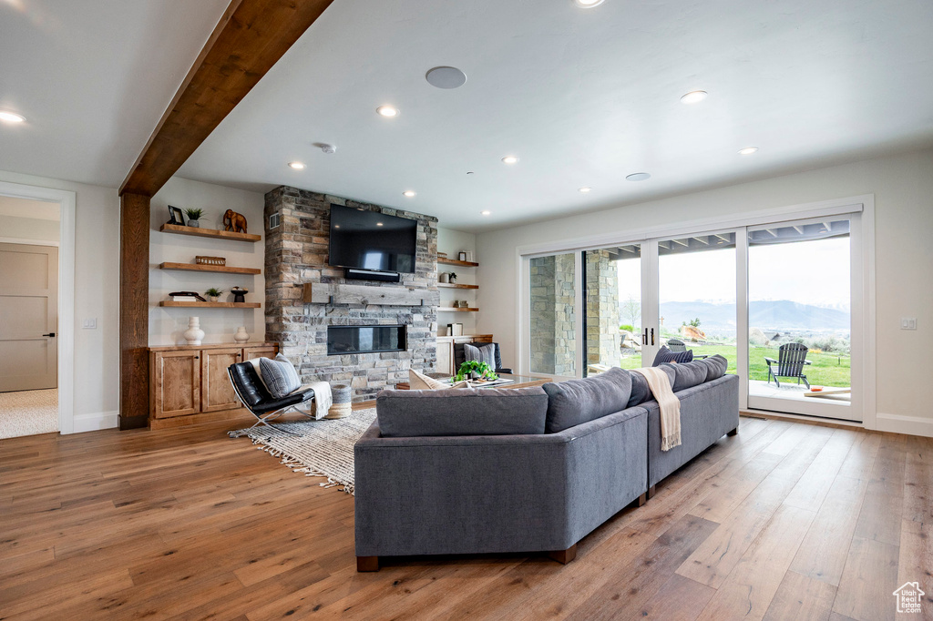 Living room with light wood finished floors, baseboards, a fireplace, and recessed lighting
