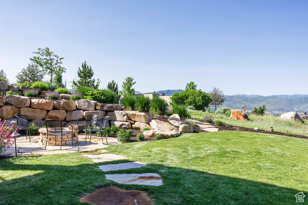 View of green lawn with a patio and a mountain view