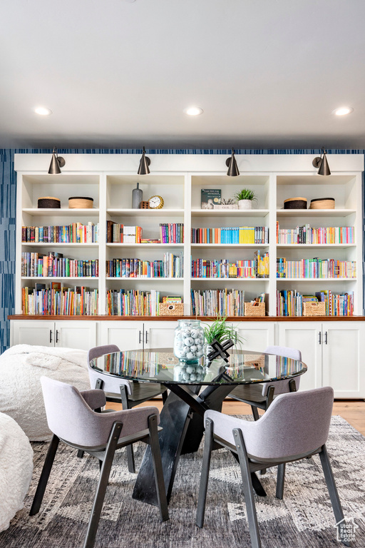 Office area featuring wall of books, wood finished floors, and recessed lighting